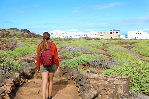 Baksidan av unga kvinnliga backpacker vandrar på våren på Lanzarote. Resenär flicka promenader mellan naturen i vägen till Orzola byn, Spanien. — Stockfoto