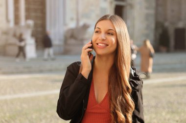 Avrupa şehir caddesinde cep telefonuyla konuşan mutlu, genç bir kadın. Yaşam tarzı portresi.