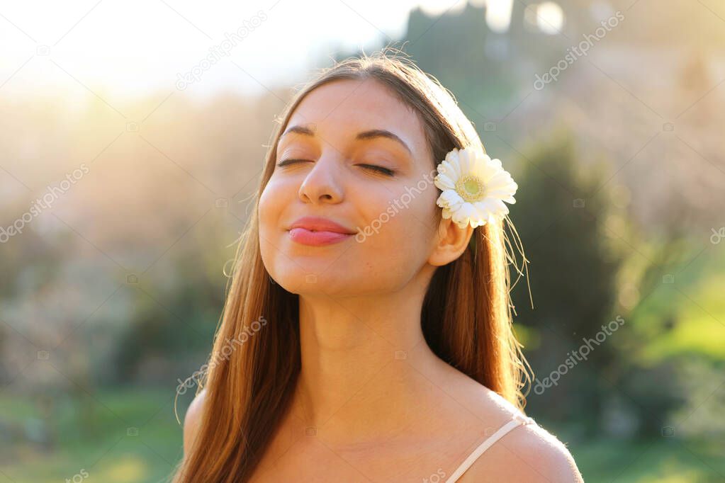 Close up portrait of Brazilian girl breathing fresh air with closed eyes and white flower on ear outdoor