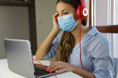 COVID-19 Pandemic Coronavirus Ev Bilgisayarından E-Öğrenci Maskesi Çalışması. Virüs hastalığı SARS-CoV-2 için evden eğitim gören genç bir kadın karantina altında. Akıllı okul konsepti.