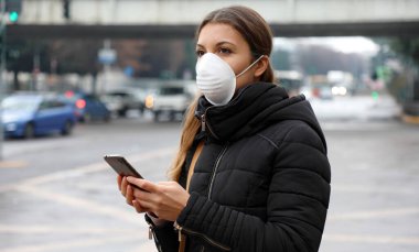 COVID-19 Pandemic Coronavirus Mobil Uygulaması - 2019-20 Coronavirus Salgınına Tepki Vermek İçin Şehir Sokağında Akıllı Telefon Uygulaması Kullanan Genç Kadın