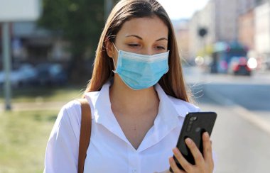 COVID-19 Pandemic Coronavirus Mobil Uygulaması - 2019-20 Coronavirus Salgınına Tepki Vermek İçin Şehir Sokağında Akıllı Telefon Uygulaması Kullanan Genç Kadın