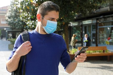 Coronavirus 2019 'daki Coronavirus salgınına tepki olarak Şehir Sokağında Akıllı Telefon Uygulaması kullanarak Temas İzleme ve Kişilik Teşhisi' ni destekleyen Kordemik Koronavirüs Genç Adam Takıyor.