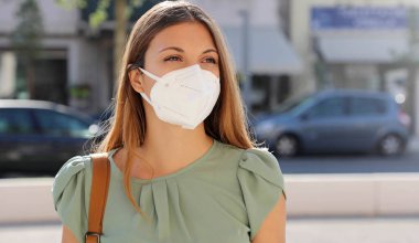 SARS-CoV-2 virüsünün yayılması için KN95 FFP2 maskesi takan şehir sokaklarındaki COVID-19 Pandemic Coronavirus Woman. Coronavirus Hastalığı 2019 'a karşı koruyucu maskeli bir kız..