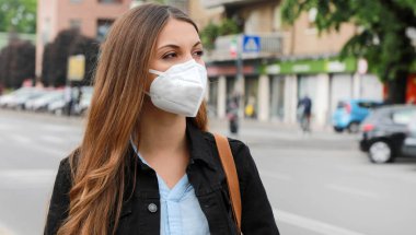 SARS-CoV-2 virüsünün yayılması için KN95 FFP2 maskesi takan şehir sokaklarındaki COVID-19 Pandemic Coronavirus Woman. Coronavirus Hastalığı 2019 'a karşı koruyucu maskeli bir kız..