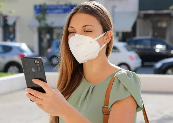 COVID-19 Mobile Application Young Woman Wearing KN95 FFP2 Mask Using Smart Phone App in City Street to Aid Contact Tracing and Self Diagnostic in Response to Coronavirus Disease 2019