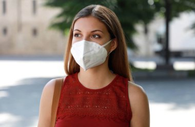 COVID-19 şehirdeki endişeli kız KN95 FFP2 maskesi takıyor SARS-CoV-2 hastalığını yaymak için. Coronavirus Hastalığı 2019 'a karşı koruyucu maskeli bir kız..