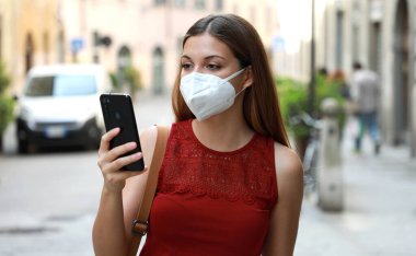 Coronavirus Hastalığı 2019 'a tepki olarak KN95 FFP2 Maske Takan Genç Kadın' ın COVID-19 Portresi Şehir Sokakları 'nda Akıllı Telefon Uygulaması ile Kişilik İzleme ve Kişilik Teşhisi