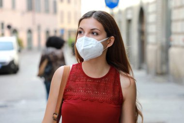 SARS-CoV-2 virüsünü yaymak için KN95 FFP2 maskesi takan COVID-19 genç kadın. Coronavirus Hastalığı 2019 'a karşı koruyucu maskeli bir kız..