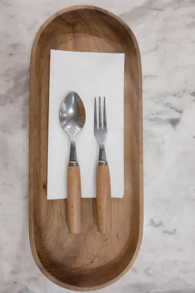 Lepel en vork op houten plaat, bovenaanzicht — Stockfoto