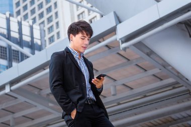 Asya iş adam ayakta ve kullanım smartphone 