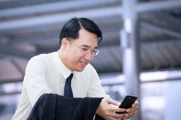 Uomo d'affari seduto e utilizzando un telefono cellulare — Foto Stock