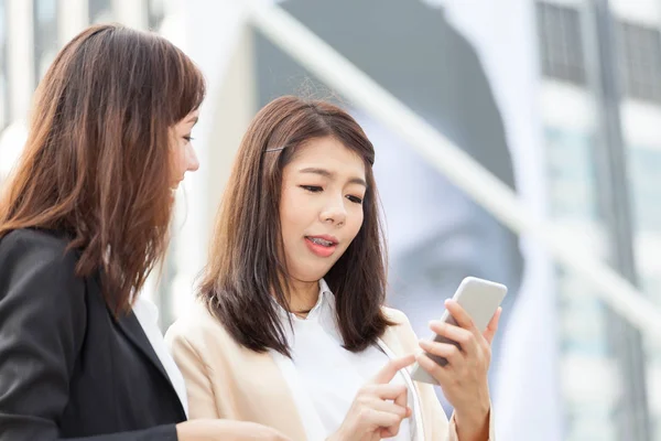 Business woman using a cell phone with colleague and discussion — Stock Photo, Image