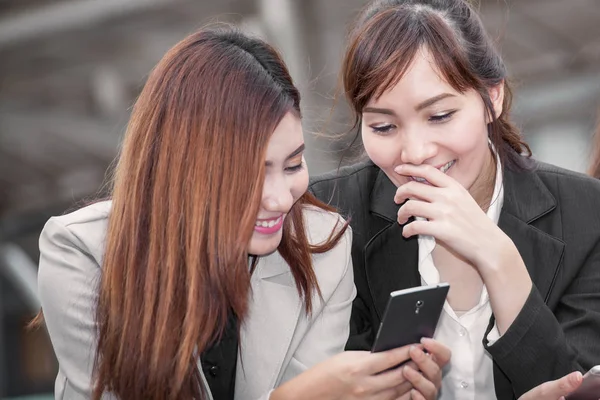 Asiática mujer de negocios feliz de usar el teléfono celular con colega —  Fotos de Stock