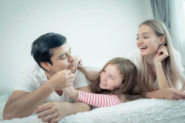 Küçük kız, anne ve babasıyla birlikte yatakta gülümsüyor. — Stok fotoğraf