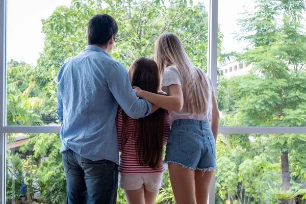 Вид сзади на отца и мать с дочерью, стоящими у окна — стоковое фото