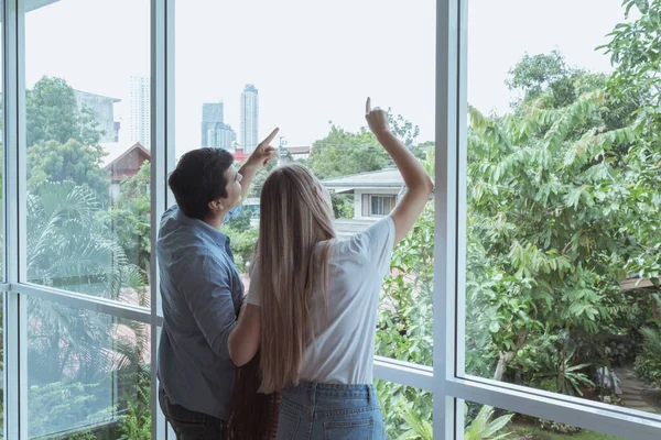 Vista posteriore di padre e madre con figlia in piedi alla finestra — Foto Stock