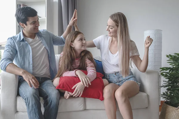 Padre y madre con hija sonriendo y sentados en el sofá toge — Foto de Stock