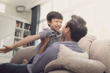 Asian family father and son playing fly in the sky together in l