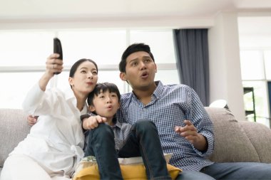 young family, father, mother and son watching TV feeling excitin