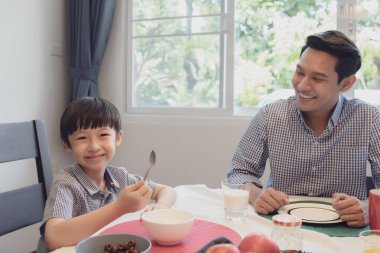 Asyalı aile, baba ve oğul akşam yemeğinde birlikte kahvaltı ediyorlar.
