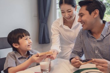 Asyalı aile, baba, anne ve oğul kahvaltı yapıyor.
