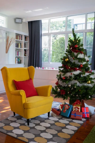 Duży żółty fotel w salonie z choinką i prezent przed — Zdjęcie stockowe