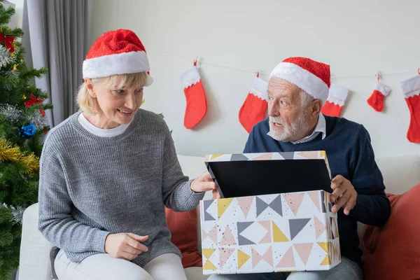 Äldre kaukasisk gammal man och kvinna hjälpa öppna stora gåva pr — Stockfoto