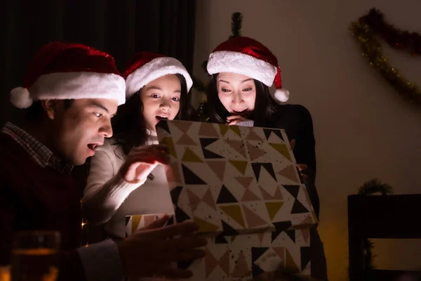 Lycklig familj, far mor dotter hjälp att öppna present b — Stockfoto