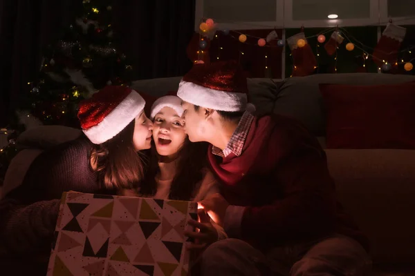 Família feliz, pai mãe beijo filha durante abrir um presente pre — Fotografia de Stock