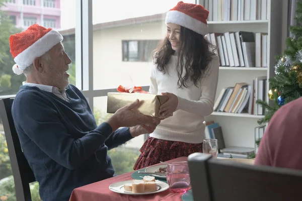 Bambina che dà un regalo o un regalo per l'uomo anziano indossare cappello rosso — Foto Stock
