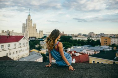 Dikiz çatı bina ve gündüz cityscape üzerinde seyir üzerinde oturan sarışın kadın