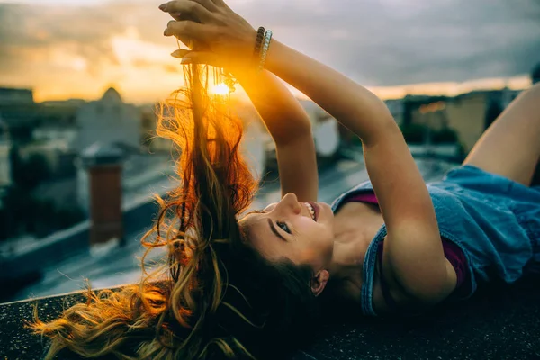 日落时躺在楼顶的年轻成年女孩 — 图库照片
