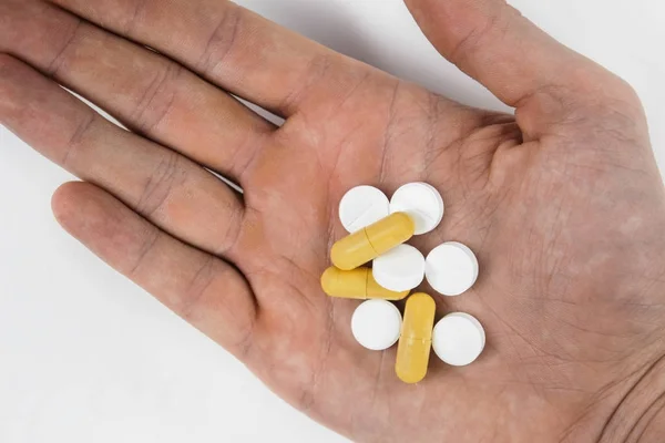 Pastillas y cápsulas medicinales en la mano sobre fondo blanco, Antibiótico, analgésico de cerca . — Foto de Stock