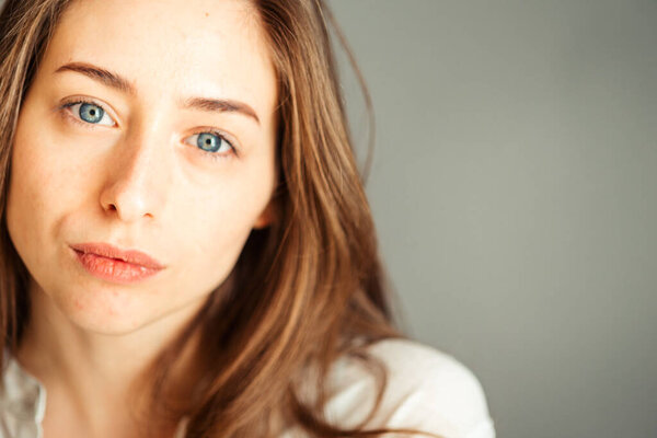 Серьезная девушка с натуральными волосами в яркой одежде на сером фоне, крупным планом. Обнажённый макияж, без ретуши
.