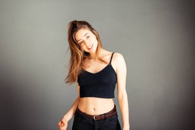 Siyah bluzlu, saçları gri arka planda olan bir kızın portresi. Makyajsız.