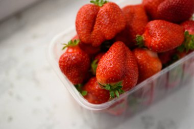 Beyaz arka planda plastik bir kutuda iyi organik çilekler. Organik ürünlerin teslimatı. organik çilek paketleme.