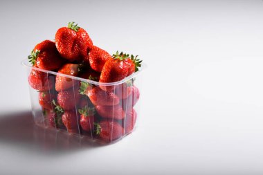 Beyaz arka planda plastik bir kutuda iyi organik çilekler. Organik ürünlerin teslimatı. organik çilek paketleme.