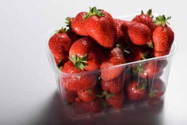 Beyaz arka planda plastik bir kutuda iyi organik çilekler. Organik ürünlerin teslimatı. organik çilek paketleme.