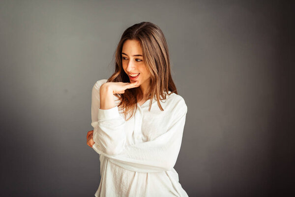 Young girl in a white shirt on a gray background. French woman in white blouse on a background of gray walls. Without retouching and makeup.