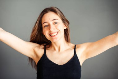 Saçları siyah bluzlu kız gülümsüyor ve mutlu bir adam. Hayatın tadını çıkar. Gri bir arka planda. Makyajsız.