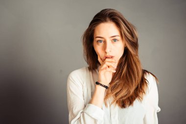 Gülümseyen kız, gri arka planda elleri yüzüne yakın, kapat. Makyajsız, rötuşsuz.