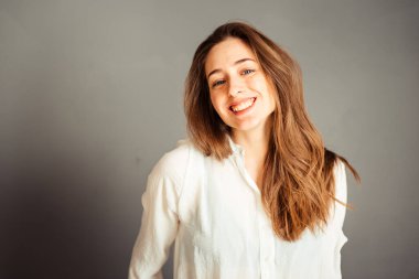 Gülümseyen kız, gri arka planda elleri yüzüne yakın, kapat. Makyajsız, rötuşsuz.