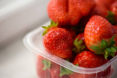 Beyaz arka planda plastik bir kutuda iyi organik çilekler. Organik ürünlerin teslimatı. organik çilek paketleme.
