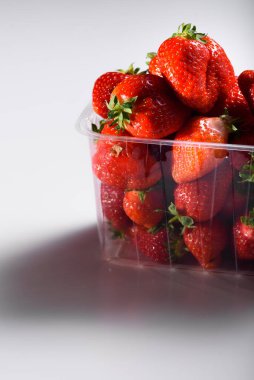 Beyaz arka planda plastik bir kutuda iyi organik çilekler. Organik ürünlerin teslimatı. organik çilek paketleme.