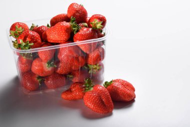 Beyaz arka planda plastik bir kutuda iyi organik çilekler. Organik ürünlerin teslimatı. organik çilek paketleme.