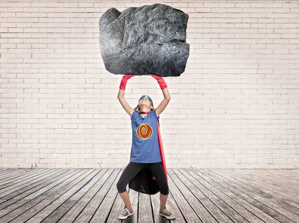 Superhero holding a heavy rock — Stock Photo, Image