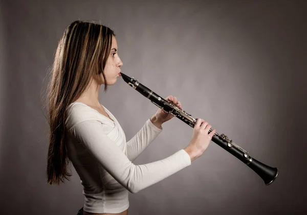 灰色の背景にクラリネットを演奏若い女性 — ストック写真
