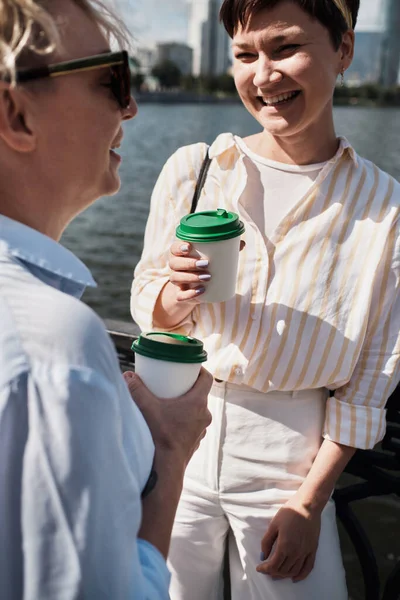 Two women walking outdoor with coffee