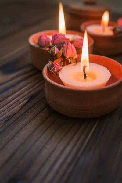 Персиковые свечи в деревянных чашках с сушеными цветами — стоковое фото